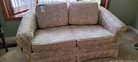 Front view of the light taupe floral loveseat showing two seat and two back cushions