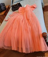 Full view of coral dress with purse on bed