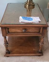 Full view of oak end table with glass top, drawer, and lower shelf