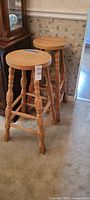 Two oak bar stools beside china cabinet