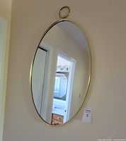 Full view of oval brass-tone mirror hanging on wall