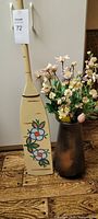 Full view of painted paddle and metal vase with silk flowers