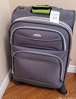 Front view of grey Samsonite suitcase showing brand badge, front zip compartments and spinner wheels