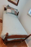 Twin maple bed fully dressed with quilt and pillow
