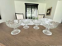 Four clear pressed-glass pedestal dessert bowls on table