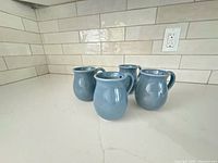 Four blue mugs arranged on countertop