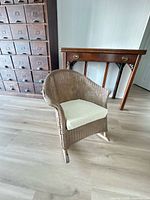 Front angle of child wicker rocking chair showing overall form and new seat cushion