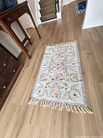 Full view of floral scatter rug showing design, colors and fringe