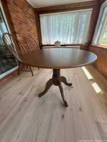 Full view of round wooden pedestal table on sun-porch floor