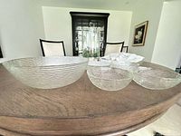 Large ribbed glass bowl with three of the smaller matching bowls displayed on table