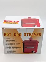 Front view of boxed red hot dog steamer showing product image and name