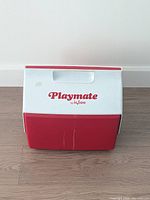 Closed cooler front view showing Playmate by Igloo logo and red front panel