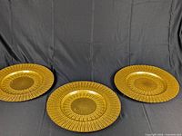 All three gold-tone charger plates on black backdrop