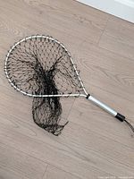 Full view of aluminum-handled landing net with black mesh and wrist cord