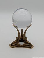 Crystal ball resting on brass dolphin stand, front view