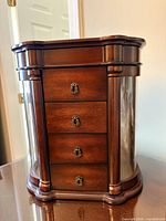 Front view of armoire closed showing four drawers and cherry finish