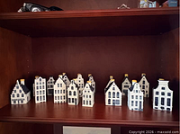 Front view of 15 ceramic canal house bottles arranged on shelf