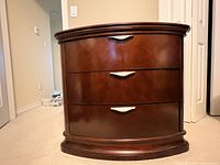 Front view of cherry-finish nightstand showing three drawers and hardware