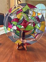 Full view of signed hand-painted art glass charger plate on stand