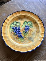 Front view showing grapevine artwork and scalloped cobalt rim