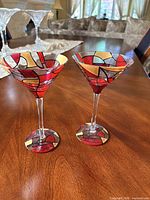 Two hand-painted martini glasses upright on wood table