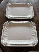 Both matching white rectangular platters with ornate borders visible
