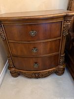 Front view of one nightstand showing three drawers, carved details, hardware