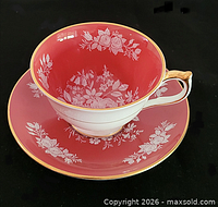Teacup on saucer showing pink interior floral design and gold trim
