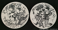 Front view of both round plaques showing illustrated scenes and hanging holes