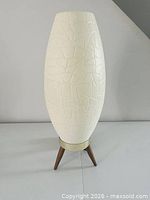 Full view of lamp showing plastic body and tripod legs