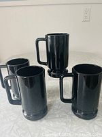 Four black amethyst glass mugs grouped on table