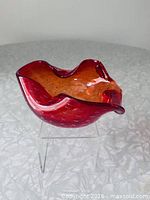 Oblique view showing ruby red exterior, amber interior, controlled bubbles, ruffled rim