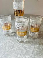Four matching Libbey highball glasses showing gold and frosted leaf pattern