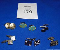 All six pairs of cufflinks arranged on blue background