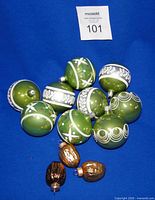 Nine green Martha Stewart Everyday blown glass ornaments and three glass walnuts displayed on blue background