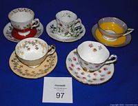 All five cup and saucer sets displayed together on blue background