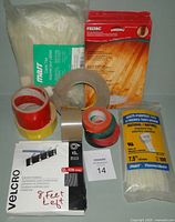 Group shot of zip ties bag, felt pads packs, tape rolls and Velcro pack