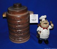 Front view of ceramic cookie jar with lid in place and resin chef figurine beside it