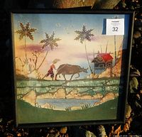 Front view of framed batik artwork showing rural scene and signature