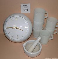 Front view of clock, six stacking mugs and mortar with pestle