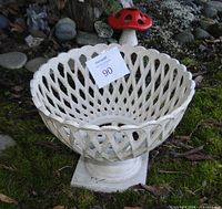 angled view of white cast iron pedestal basket planter on moss