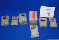 All unopened Organ needle packs arranged by type with MaxSold card showing lot number