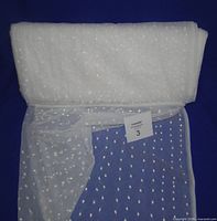 Full roll of white dotted netting fabric on blue background