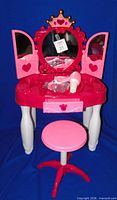 Vanity with mirror doors open, accessories on tabletop, stool in foreground