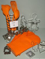 Overall lot showing orange mitts, utensils in chrome holder, and some cookie cutters