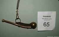 Side view of brass and copper boatswain whistle attached to chain