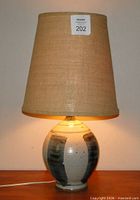 Lamp illuminated showing full view with shade and pottery base