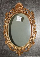 Front view of gold ornate oval mirror showing frame and glass