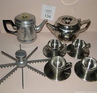 Group shot of percolator, teapot, four OGGI cups with saucers, pie sectioner