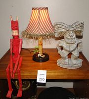 Group shot of devil doll, lamp, and Tiki statue on shelf